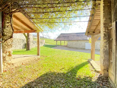 Vue depuis la pergola sur la pelouse et les dépendances